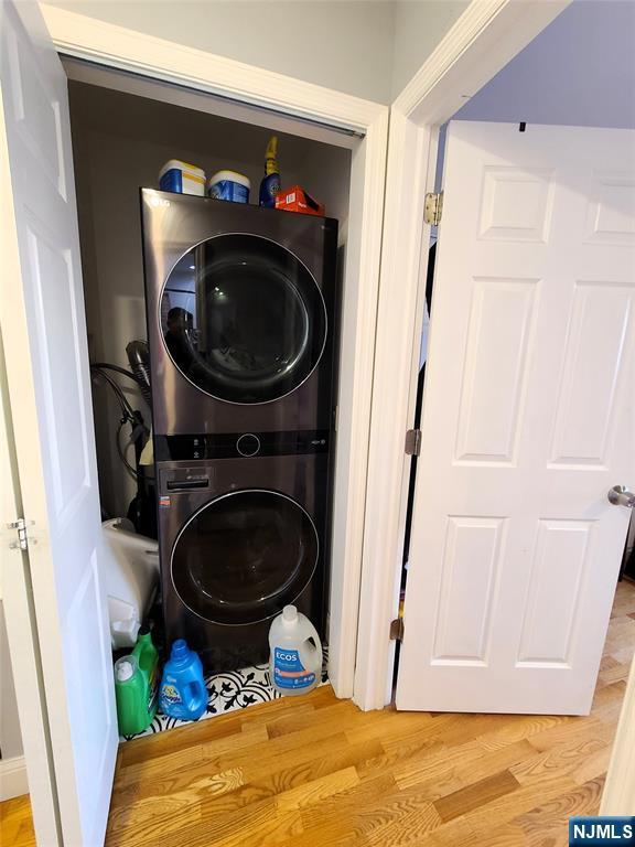 laundry room featuring stacked washer / dryer, laundry area, and wood finished floors