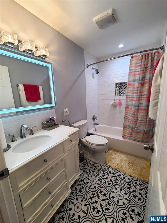 full bath featuring visible vents, decorative backsplash, shower / tub combo with curtain, tile patterned floors, and vanity