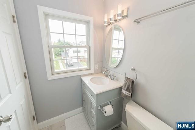 bathroom featuring toilet, vanity, and baseboards