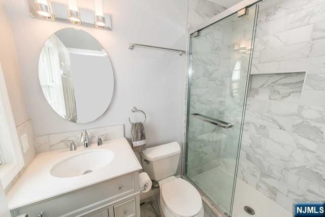 bathroom with a stall shower, vanity, and toilet