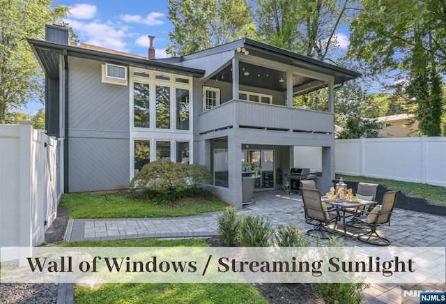 back of property with a balcony, a patio area, a fenced backyard, and a chimney