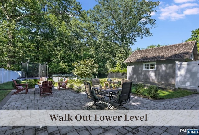 view of patio featuring a fenced backyard, a trampoline, and outdoor dining space