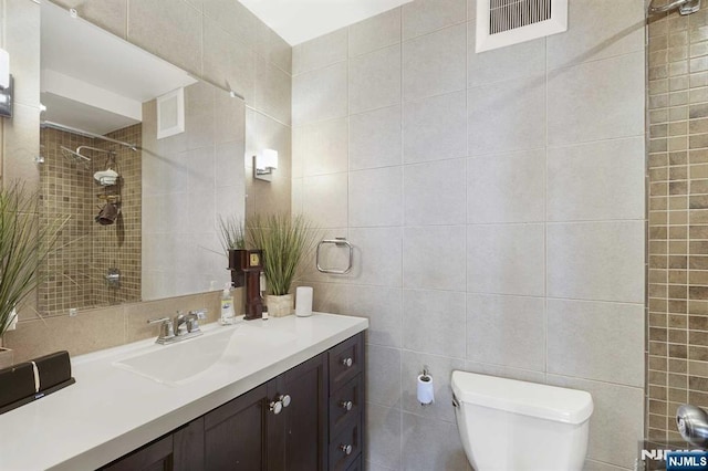 bathroom with toilet, walk in shower, tile walls, and vanity