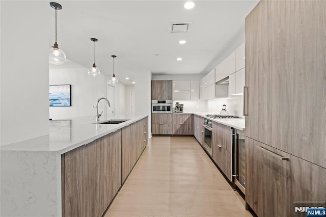 kitchen with decorative light fixtures, white cabinetry, a sink, modern cabinets, and oven