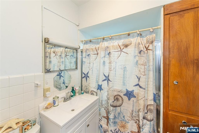 full bath featuring curtained shower, vanity, and tile walls