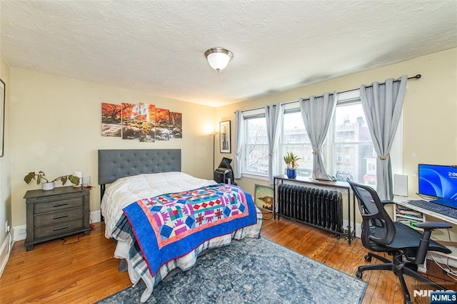 bedroom featuring radiator heating unit, wood-type flooring, and a textured ceiling