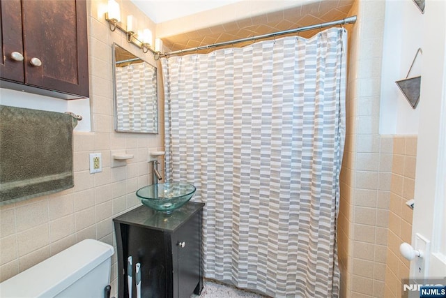 bathroom with toilet, a shower with shower curtain, vanity, and tile walls