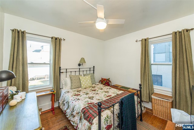 bedroom with multiple windows, dark wood finished floors, and ceiling fan