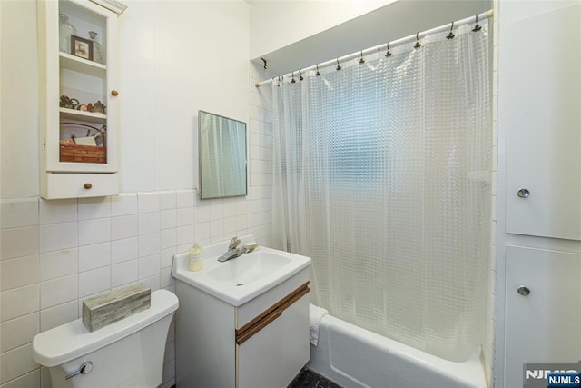 bathroom with toilet, shower / bath combo, tile walls, and vanity