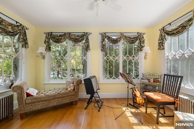 sunroom with radiator heating unit, wood finished floors, and a healthy amount of sunlight