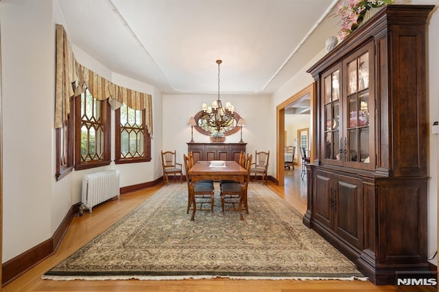 dining space with baseboards, a notable chandelier, radiator heating unit, and wood finished floors