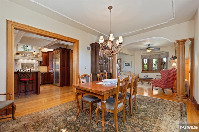 29 Raymond Ave, Rutherford, NJ 07070 - dining area with ornate columns, arched walkways, light wood-style floors, and ceiling fan with notable chandelier