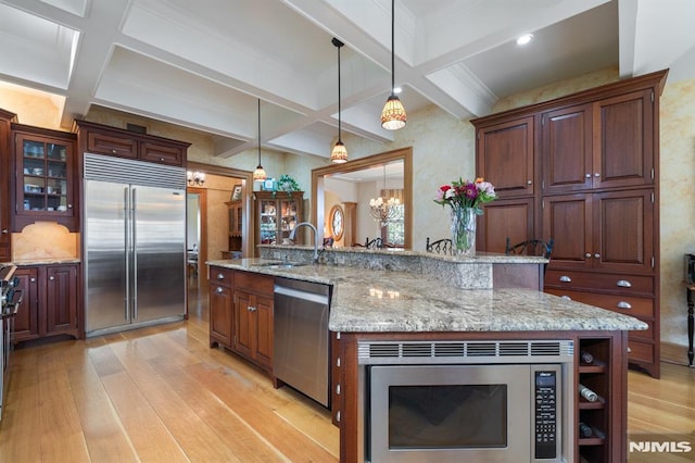 kitchen with light wood-style floors, coffered ceiling, and built in appliances