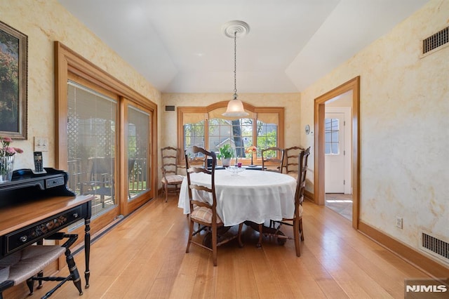 dining area featuring baseboards, visible vents, lofted ceiling, and light wood-type flooring