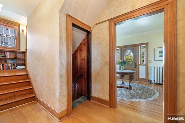 corridor with baseboards, stairs, radiator, and wood finished floors
