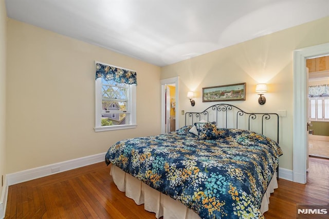 bedroom featuring baseboards, wood finished floors, and radiator heating unit