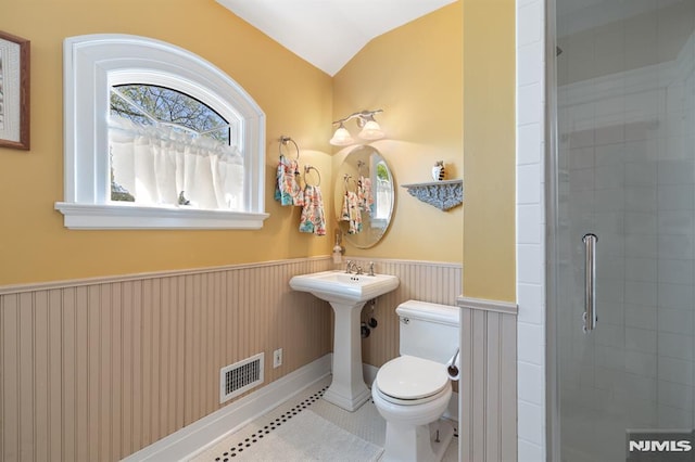 full bathroom featuring wainscoting, toilet, vaulted ceiling, visible vents, and tiled shower