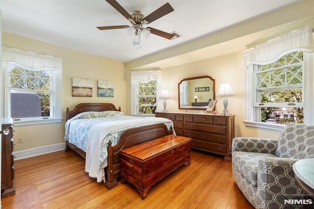 bedroom featuring a ceiling fan, visible vents, multiple windows, and light wood-style flooring