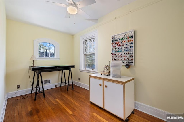 interior space with wood-type flooring, a ceiling fan, baseboards, and visible vents