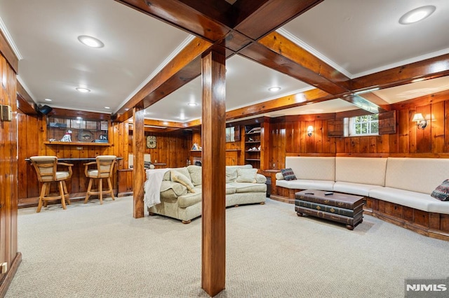 living area featuring carpet flooring, wood walls, bar area, and ornamental molding
