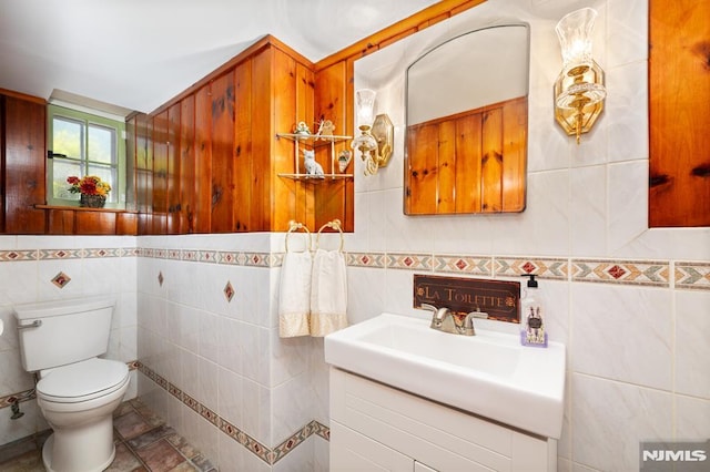 half bath with vanity, toilet, and tile walls