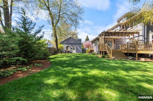 view of yard featuring a wooden deck, fence, a pergola, and an outbuilding
