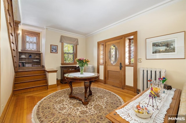 entrance foyer with stairway, ornamental molding, wood finished floors, and radiator