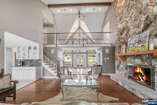 living area with stairs, a fireplace, wood finished floors, and beam ceiling