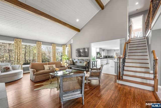 living room with stairs, high vaulted ceiling, beamed ceiling, and wood finished floors