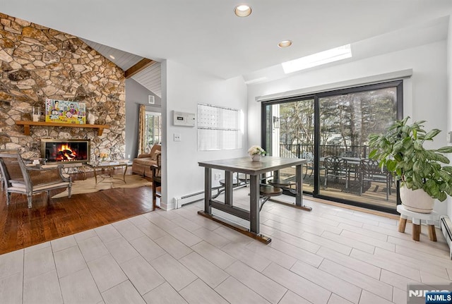 dining space featuring light wood finished floors, a baseboard radiator, vaulted ceiling with beams, a stone fireplace, and recessed lighting