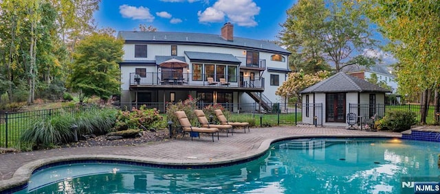 rear view of house featuring a patio, a chimney, fence, and a fenced in pool