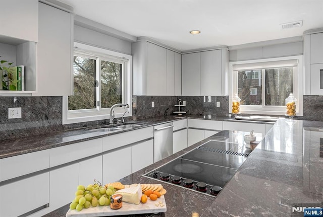 kitchen with dark stone counters, a sink, visible vents, and white cabinets