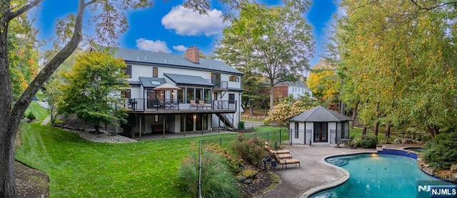 rear view of house with a yard, a chimney, a patio area, fence, and an outdoor structure