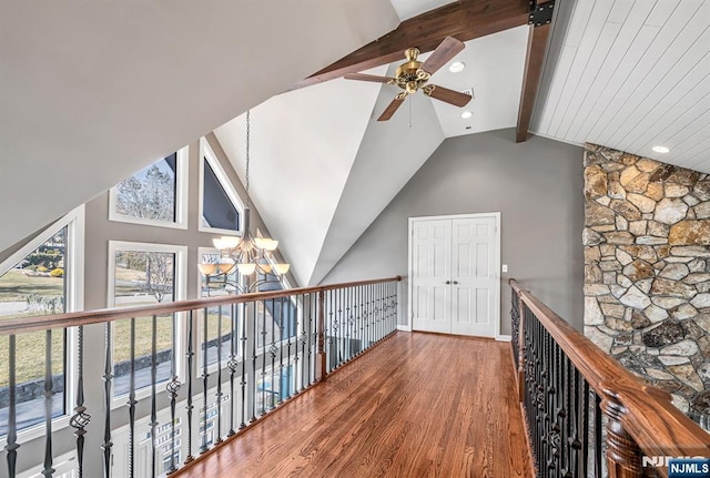 hallway with lofted ceiling with beams, baseboards, wood finished floors, and a notable chandelier