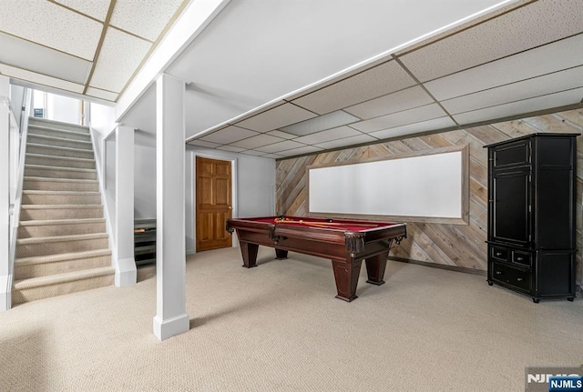 recreation room featuring a paneled ceiling, carpet flooring, and wooden walls