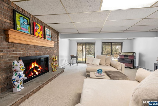 carpeted living area featuring a brick fireplace, a baseboard radiator, baseboards, and a drop ceiling