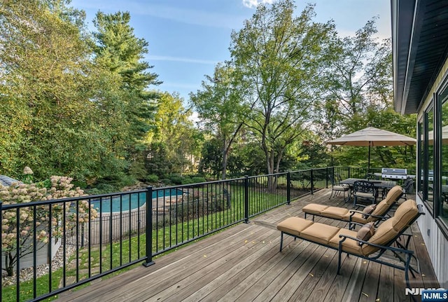 wooden deck with a fenced in pool and outdoor dining space