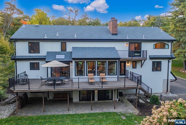 back of house with a chimney, a shingled roof, a lawn, stairway, and a deck