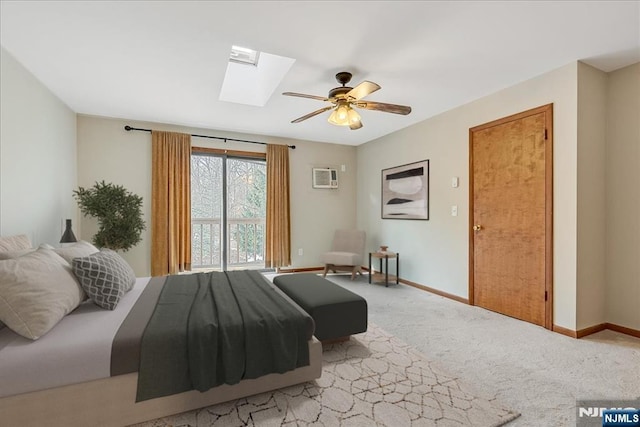 bedroom with light carpet, a skylight, baseboards, and a wall mounted air conditioner