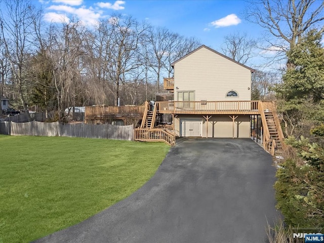 view of side of property with fence, stairway, a deck, and a lawn