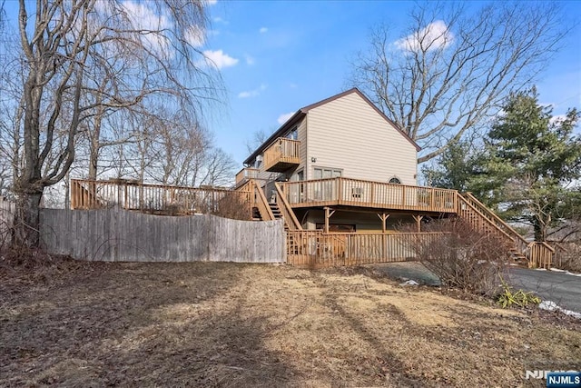 rear view of house featuring stairs, fence, and a wooden deck