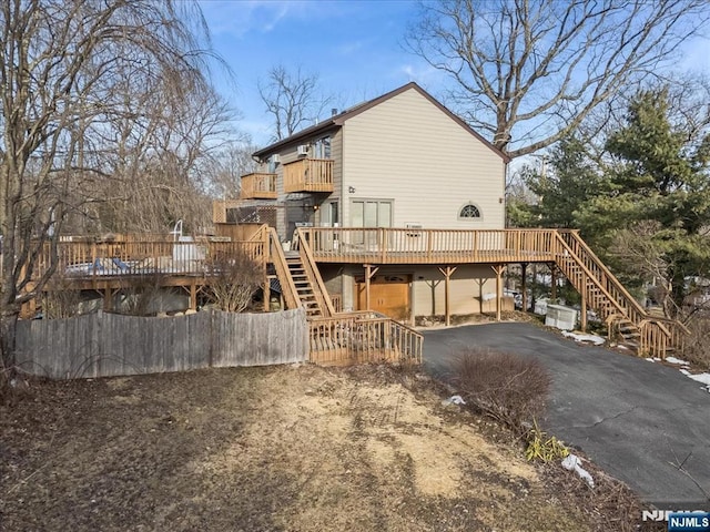 back of house with a deck, aphalt driveway, stairway, and fence