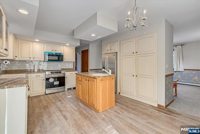 kitchen featuring decorative light fixtures, stainless steel electric range oven, a kitchen island, a sink, and light wood-type flooring