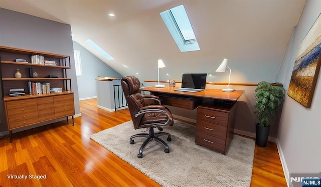 home office with vaulted ceiling with skylight, baseboards, and light wood finished floors