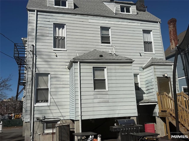 rear view of house with roof with shingles