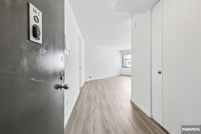 hall featuring baseboards and light wood-style floors