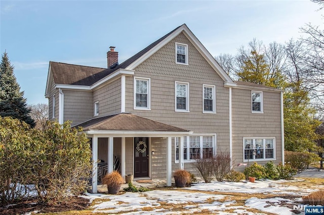 shingle-style home with a shingled roof and a chimney