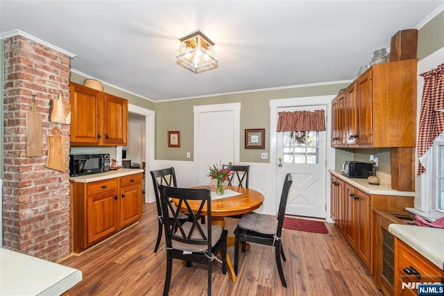 dining room featuring ornamental molding, a wainscoted wall, and wood finished floors