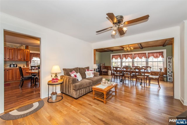 living room featuring ceiling fan with notable chandelier, ornamental molding, light wood-style flooring, and baseboards