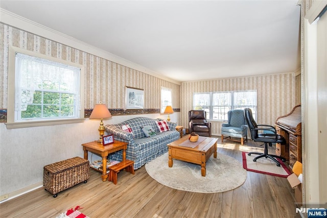 living area with wood finished floors, crown molding, and wallpapered walls